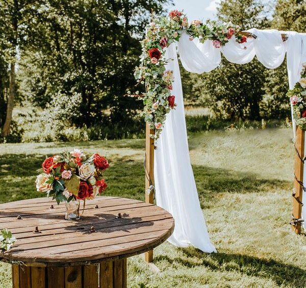 Decorating the arch with flowers and fabric for a wedding ceremony in nature